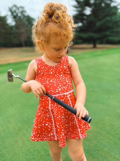 Child in red dress holding toddler golf club
