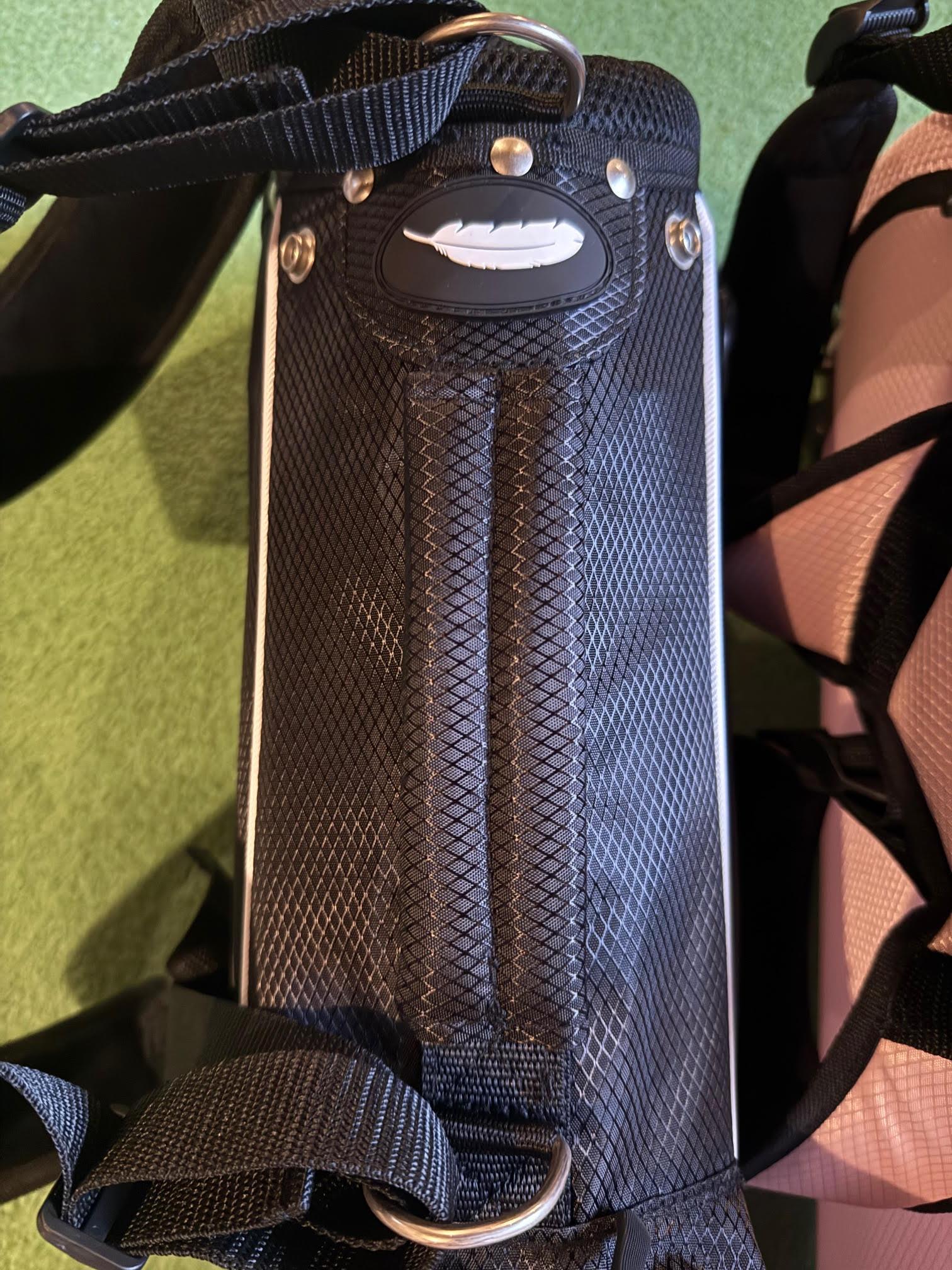 Black kids golf bag with a feather label on a green background